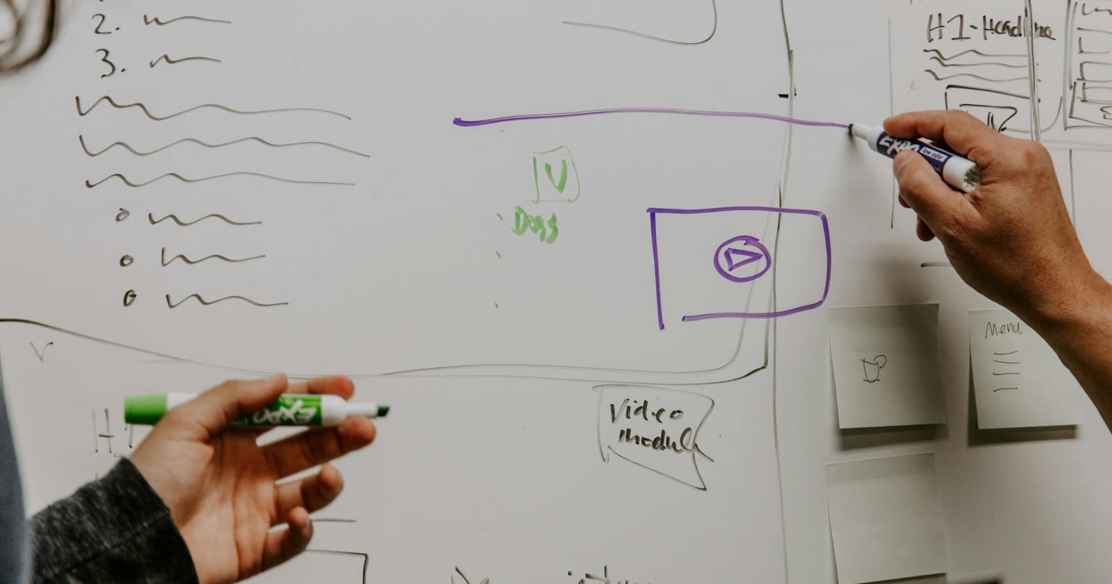 Two colleagues working through a plan on a whiteboard