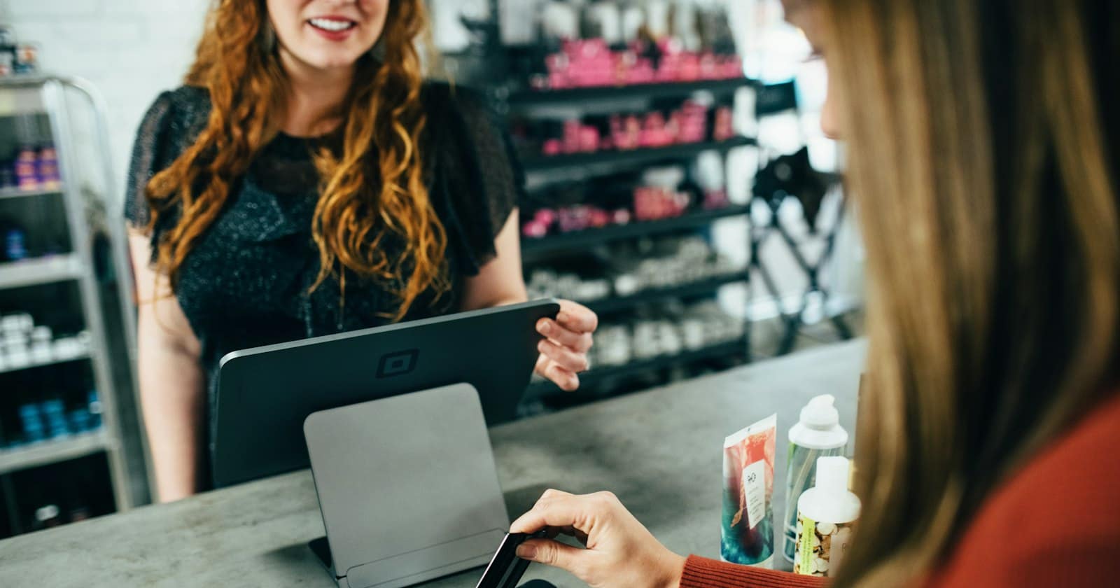 A customer holding a phone with an open chat while paying at a small shop counter