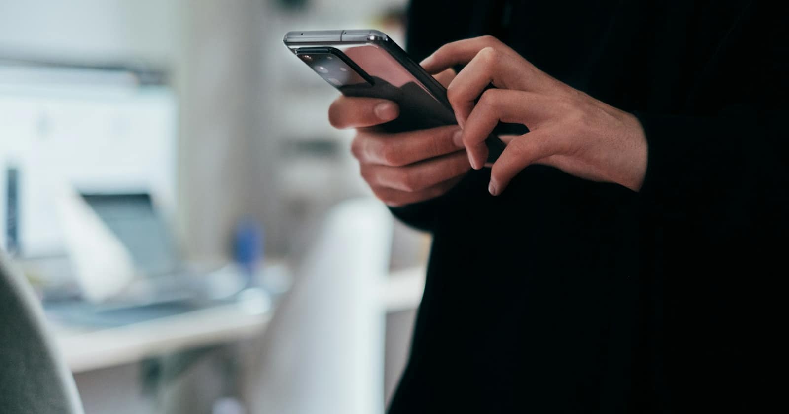 A hand holding a phone showing a messaging app