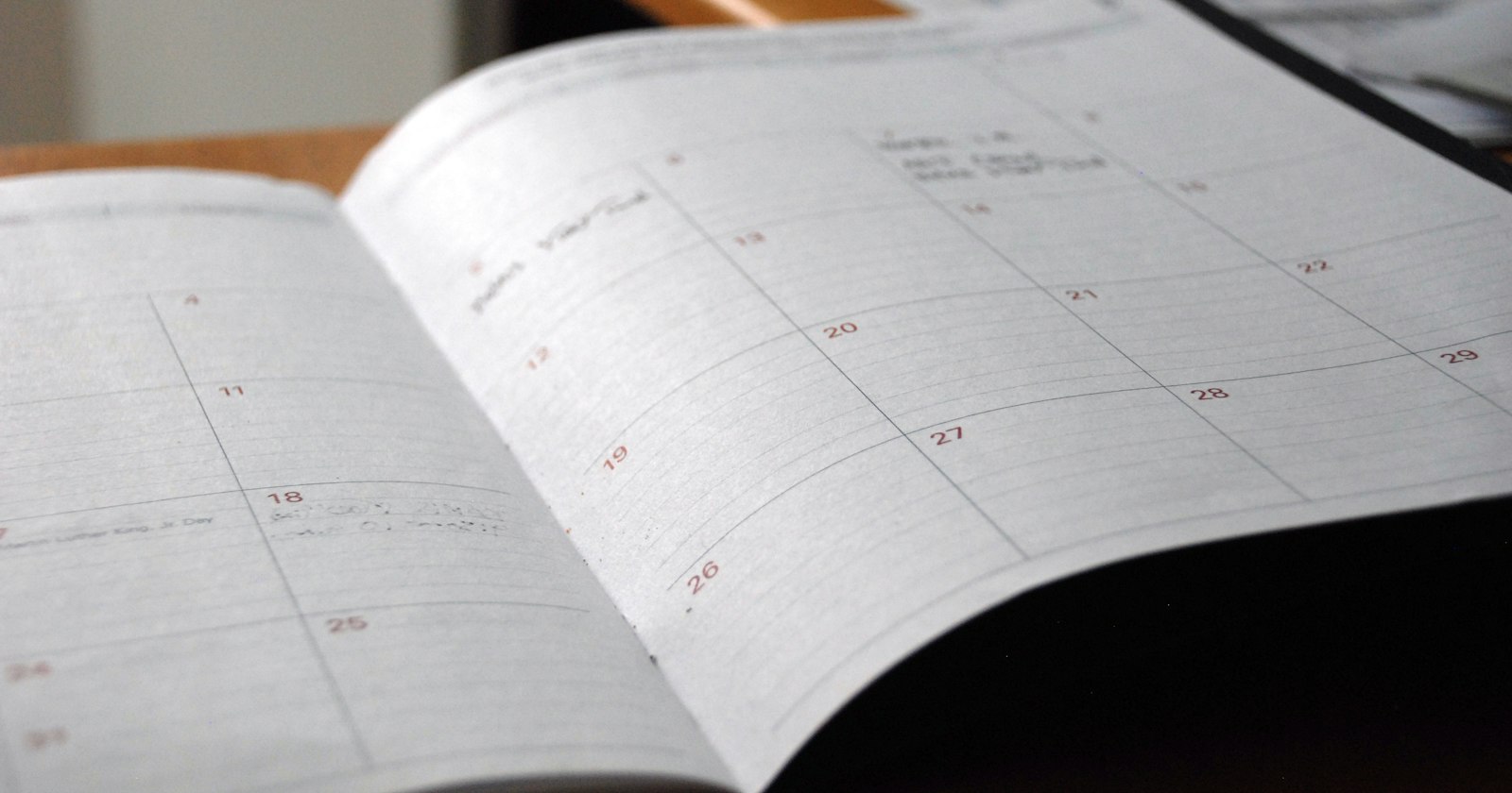 An open monthly planner on a desk, with a few days already filled in.